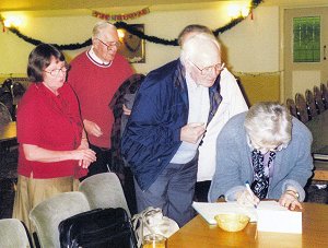 Our Treasurer,Barbara, watches as members, including Sheila Skitt, sign in.